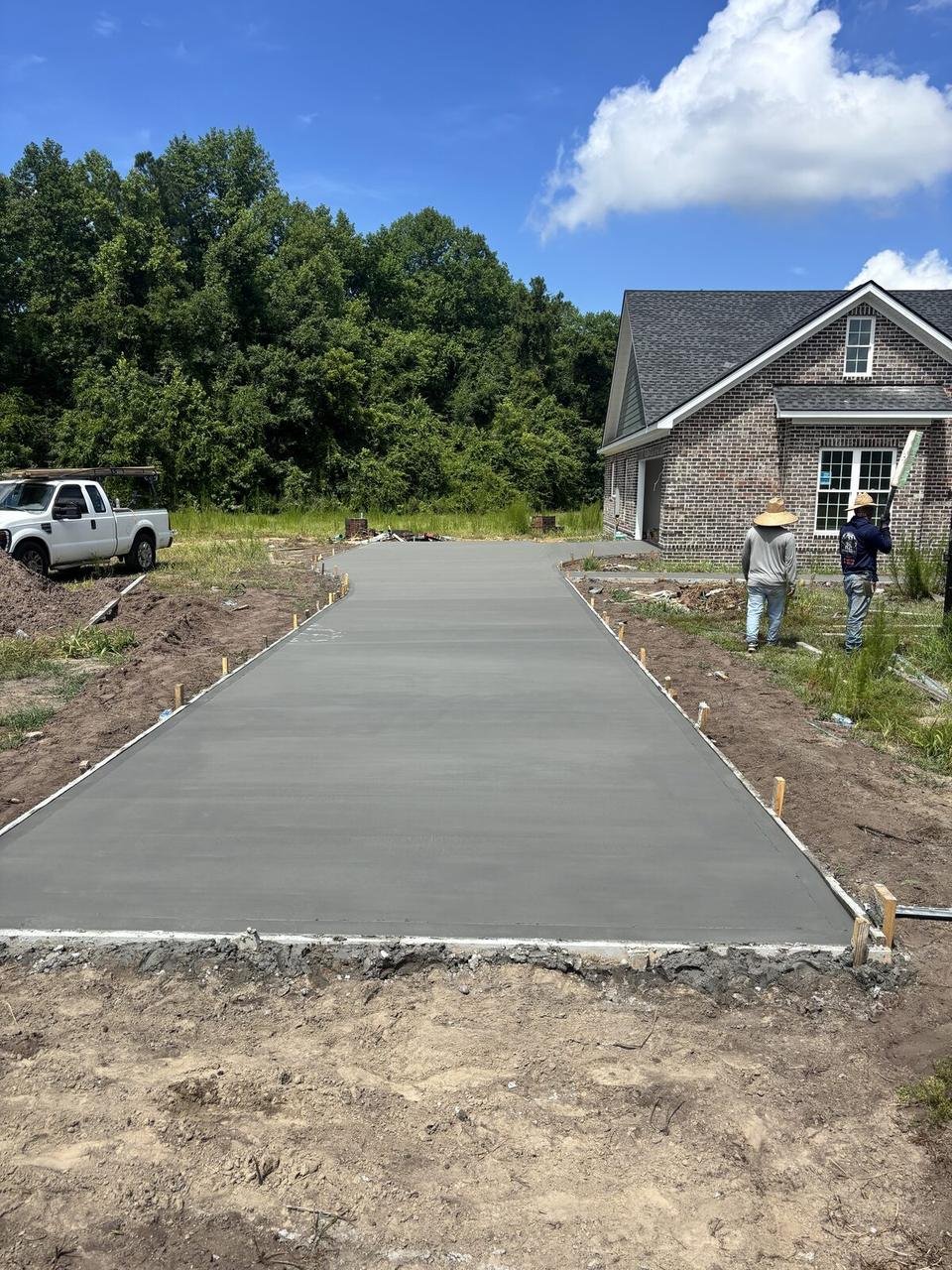 New concrete driveway leading to a brick home